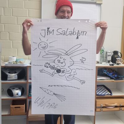Bild vergr&ouml;&szlig;ern: Karsten Teich h&auml;lt sein gemaltes Bild f&uuml;r die Klasse 2b hoch
zu sehen ist der Hase Jim Salabim mit einer Gitarre