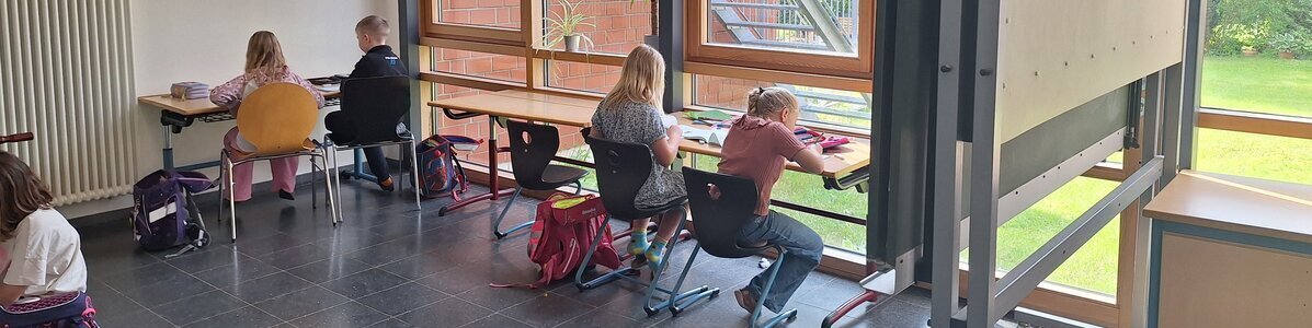 Grundschulkinder arbeiten au&szlig;erhalb des Klassenraums im Foyer.